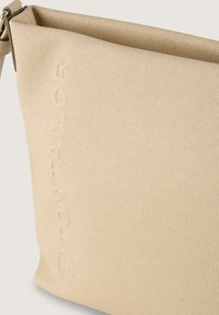 Beżowa torba na ramię o teksturowanej powierzchni i minimalistycznym designie. Posiada wytłoczone logo, górne otwarcie, czyste linie i brak widocznych elementów metalowych.