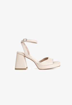 Beige hoge hakken sandalen met een open teen, een brede blokhak en een enkelbandje, met een gladde leren textuur en een platformzool.