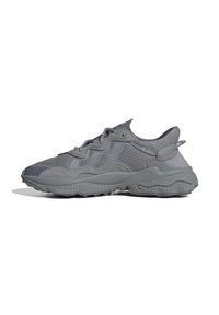 Sneaker atletici grigi con materiali in rete e sintetici, caratterizzati da un design testurizzato, linguetta imbottita e una robusta suola in gomma.