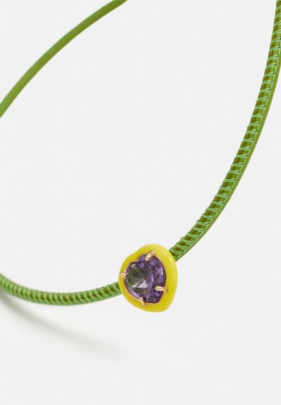 Zeleno pleteno zapestnico z rumeno srčno podrobnostjo, ki ima vijoličen dragulj v središču. Gladka tekstura in živahne barve.