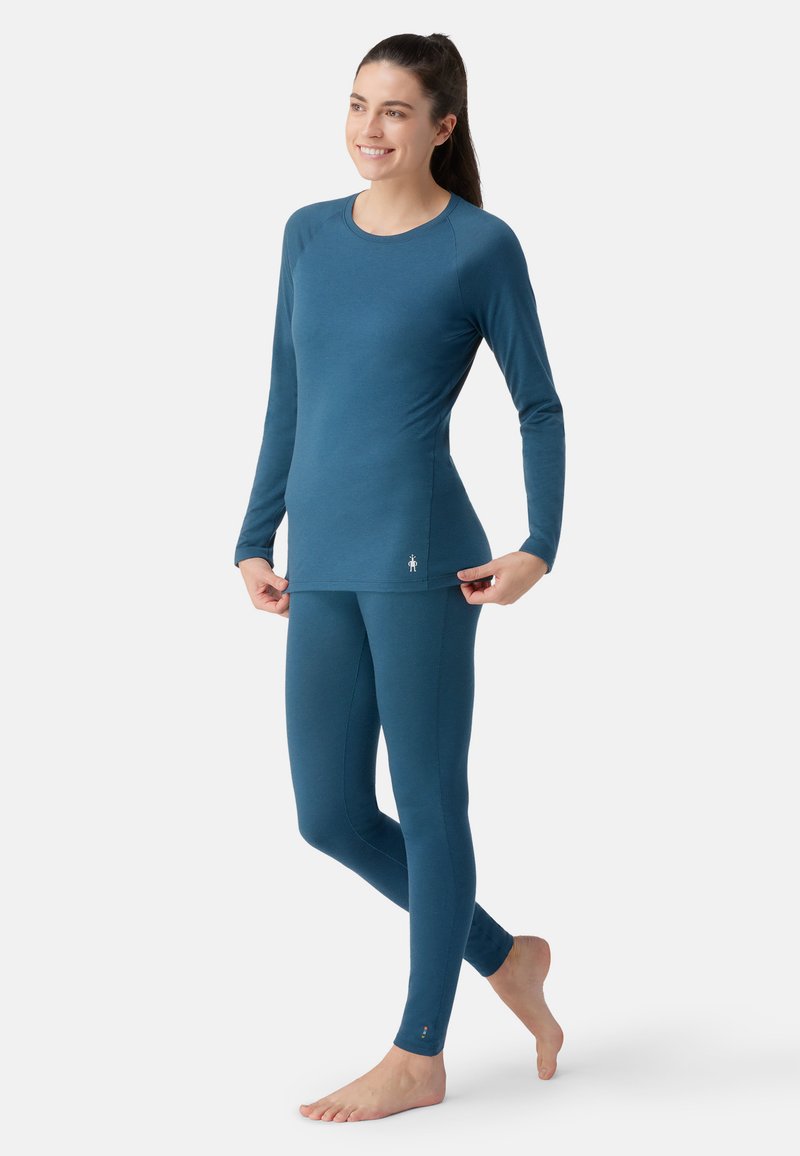 Blå langærmet top og matchende leggings i blød, strækbar stof. Enkel design med diskret logo i kanten og slank pasform.