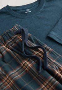 Dark teal long-sleeve shirt paired with dark green plaid pajama pants featuring brown and cream lines, elastic waistband, and drawstring.