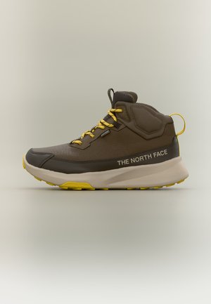 Brun og gul midt-top vandresko med gule snørebånd, hvid sål og "THE NORTH FACE" branding på siden.