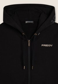 Felpa nera con zip e cappuccio, con lacci, zip dorata e ribattini, e logo "FREDDY" stampato sul petto e all'interno del colletto.