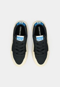 Sneakers neri in tela con suole in gomma beige, con un'accents blu sulla linguetta e lacci neri. Marchio Converse sulla linguetta.