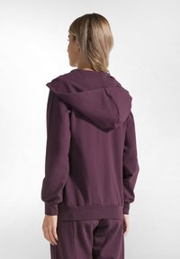 Felpa viola con una vestibilità comoda, caratterizzata da un ampio cappuccio, polsini e orlo a coste. Tessuto morbido e liscio senza motivi o decorazioni visibili.