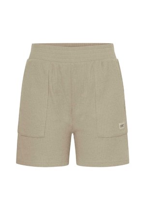Pantalones cortos de punto texturizado beige con cintura elástica y dos grandes bolsillos delanteros tipo parche, uno de ellos con una pequeña etiqueta de la marca.