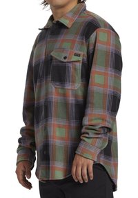 Ruitjes flanellen shirt in groen, zwart en oranje. Voorzien van een borstzak en knoopsluiting. Zachte textuur met lange mouwen.