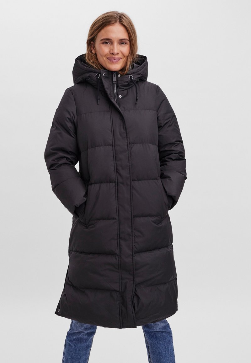 Manteau coupe-vent noir avec capuche, présentant un design matelassé, une fermeture éclair à l'avant et des poches latérales. Le tissu est lisse et isolant.