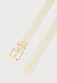 Κρέμ δερμάτινη ζώνη με λαμπερή χρυσή ορθογώνια αγκράφα και ομαλή υφή. Διαθέτει πολλές οπές για ρύθμιση και ελάχιστες ραφές.