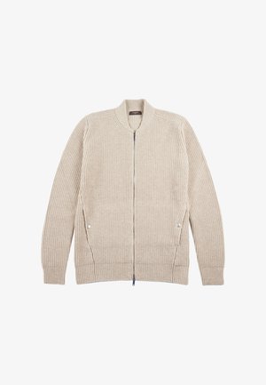 Cardigan beige tricoté avec une fermeture éclair sur le devant, texture côtelée et détails de couture latérale. Il présente un col rond et un motif rayé le long des manches.