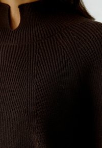 Bruine gebreide sweater met een hoge kraag en ribbelstructuur, met subtiele verticale lijnen en een ontwerp met een open hals.