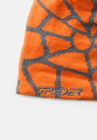 Narancssárga kötött sapka szürke geometriai mintával és hímzett "SPYDER" logóval a szélén. Puha tapintás, testhezálló kialakítás a melegségért.