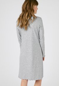 Vestido gris con relieve, de manga larga y hasta la rodilla, con un dobladillo ondulado. Textura suave, adecuada para uso casual.