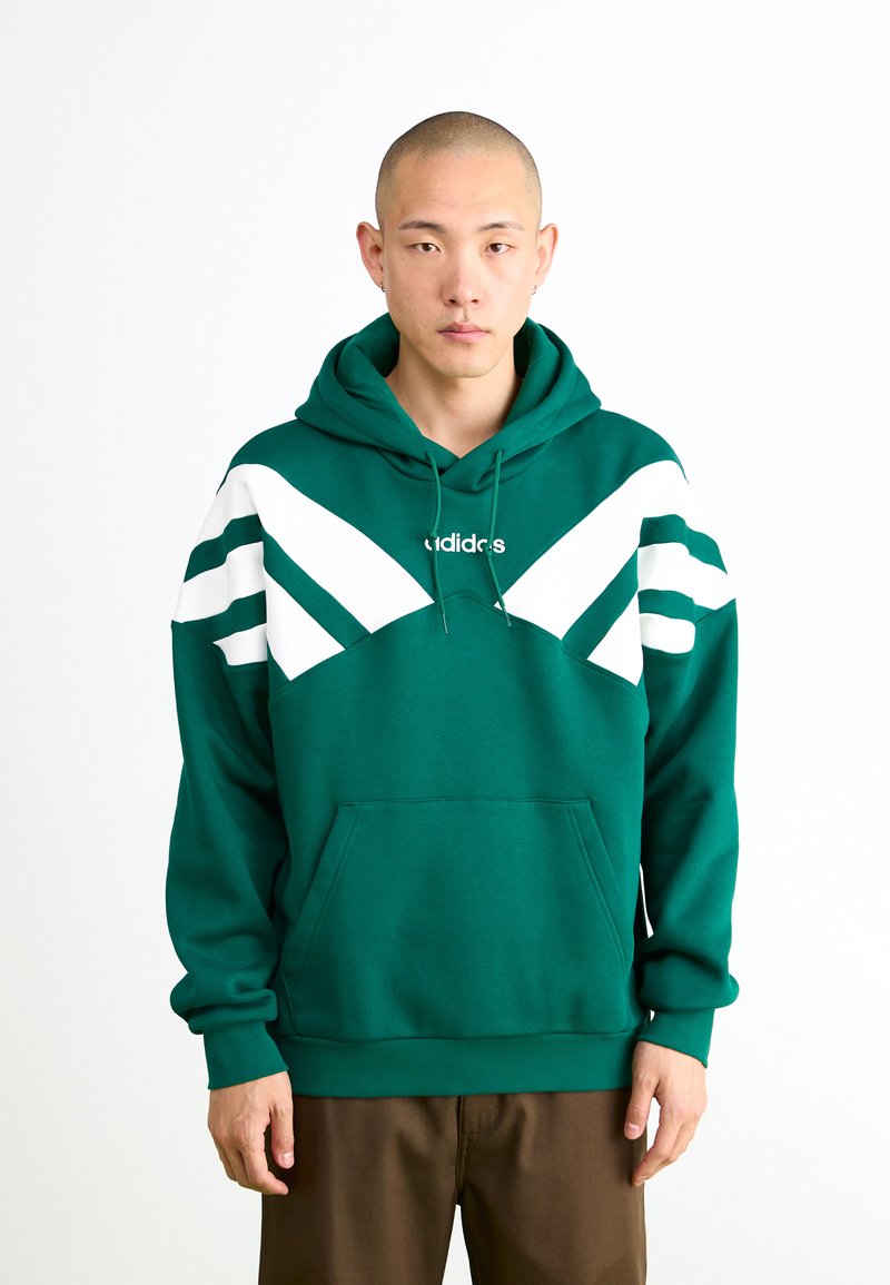 Sweatshirt verde com capuz, feito de algodão, com um bolso frontal, apresentando riscas diagonais brancas no peitoral e o logotipo da Adidas.