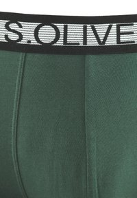 Zelene bombažne bokserice z črnim elastičnim pasom, na katerem je napisan tekst "S.OLIVER" v belem. Gladka tekstura in prilegajoča zasnova.