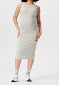 Šedé žebrované šaty bez ruk�ávů se štíhlým střihem, do délky ke kolenům. V kombinaci s bílými teniskami a světle šedými ponožkami. Jednoduchý design, bez viditelných vzorů.