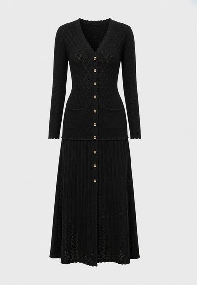 Robe noire en maille à manches longues avec col en V, boutons dorés sur le devant, deux poches avant et tissu texturé à motifs sur toute la surface.