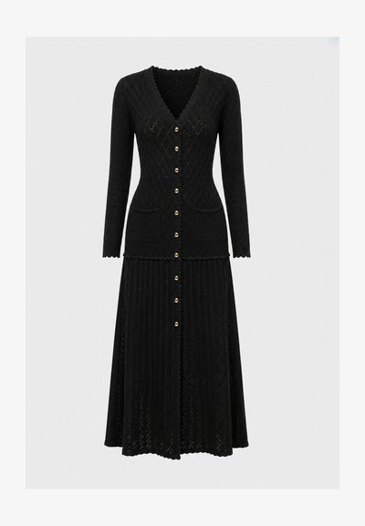 Robe noire en maille à manches longues avec col en V, boutons dorés sur le devant, deux poches avant et tissu texturé à motifs sur toute la surface.