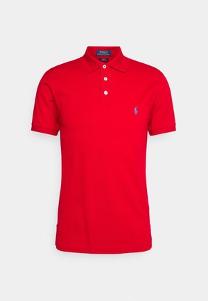 Polo rouge à manches courtes avec trois boutons blancs, col et petit logo bleu brodé sur la poitrine gauche.