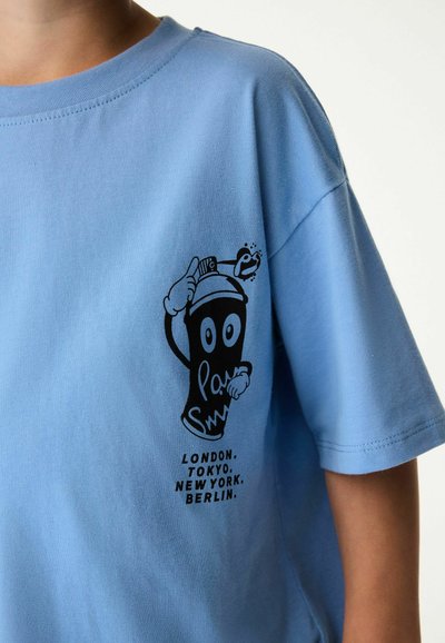 Ljusblå bomullströja med korta ärmar. Har en svart grafisk design av en sprayburksfigur och text som listar stadnamn.