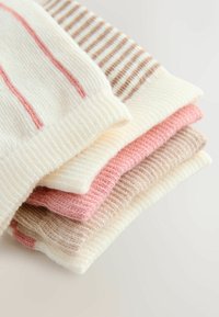 Grămadă de șosete din material tricotat moale. Caracteristici: culori pastel roz și bej, dungi subțiri și groase, și tivuri striate.