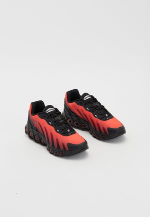 Røde og sorte atletiske sko med et strømlinet design, tekstureret overdel og karakteristiske polstringspods langs sålen.