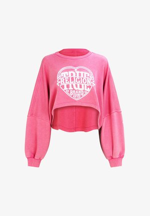 Sweat-shirt court rose avec des manches larges et bouffantes. Présente un motif cœur blanc avec le texte "TRUE RELIGION BRAND JEANS" en lettres grasses.