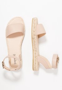 Beiga lädersandaler i espadrille-stil med ankelremmar och flätade jutesulor, visade från ovan och sidan på vit bakgrund.