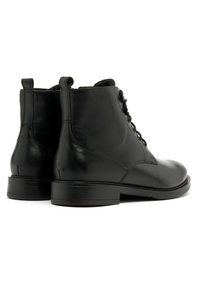 Czarne skórzane botki za kostkę o gładkiej fakturze, okrągłym nosku, sznurowanym przodzie i niskim, piętrowym obcasie. Zawierają pętlę do wsuwania z tyłu.