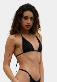 Czarny bikini z trójkątnym stanikiem i minimalnym majteczkami, z cienkimi ramiączkami i złotymi detalami. Gładka faktura materiału.