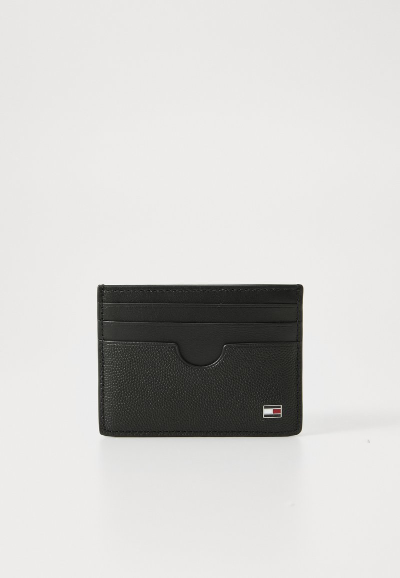 Black leather cardholder with multiple card slots, textured surface, and a small logo in red, white, and blue at the bottom right corner.