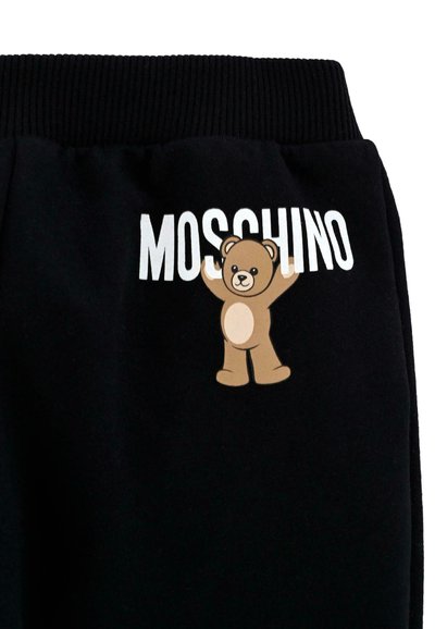 Zwarte sweatpants met een geribbelde tailleband, een berenafbeelding in bruin en crèmekleur, en de merknaam "MOSCHINO" in vetgedrukte witte letters.