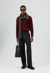 Gebreide bordeauxrode trui, grijze sjaal, antraciet broek, zwarte schoenen en een zwarte leren tas; strak, op maat gemaakt ontwerp met gestructureerde stof.