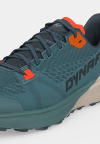 Chaussure de trail running bleue et orange avec tige en mesh, lacets détaillés et logo "DYNAFIT" sur le côté.