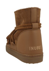Botas de tobillo marrones con un upper de ante, acentos de cuero, cordones trenzados y un talón elevado con el nombre de la marca grabado. Suela texturizada.
