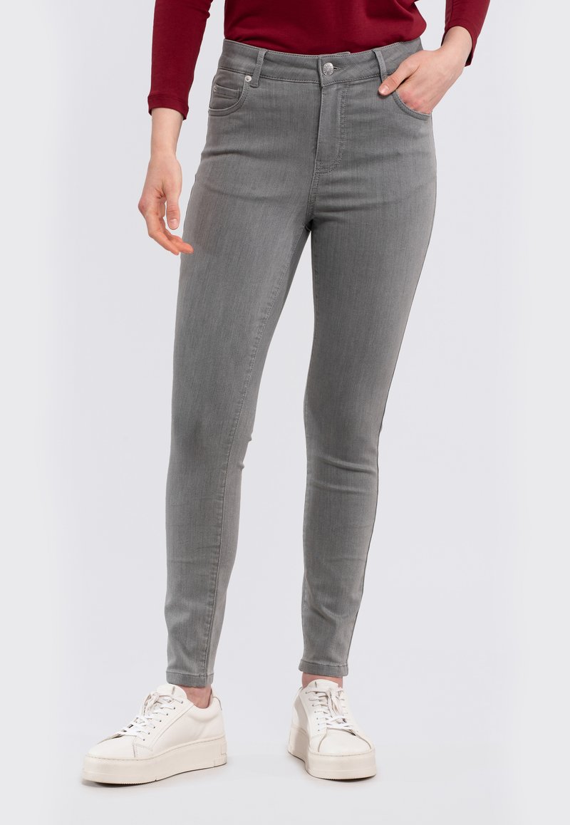 Slim-fit grey denim jeans with a high waist, five pockets, and subtle stitching details, paired with white sneakers.