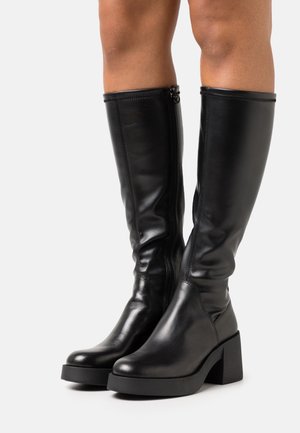 Bottes noires en cuir montant jusqu'au genou avec un talon épais, une fermeture éclair latérale, une texture lisse et un design élégant, dotées de détails de couture renforcée.