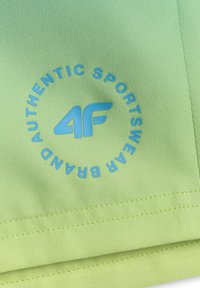 Tissu vert vif avec ourlet à double surpiqûre, comportant un logo circulaire bleu « 4F Authentic Sportswear Brand ».