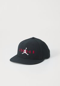 Sort snapback cap med flad skygge, med rød "JORDAN" tekst og hvid springende basketballspiller logo i fronten.