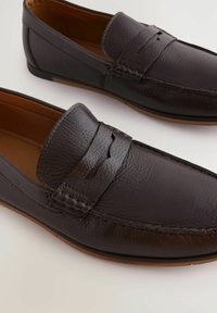 Mørkebrune læder loafers med en tekstureret overflade, der har et vævet detaljer foran og en glat sål. Letvægtsdesign, slank form.