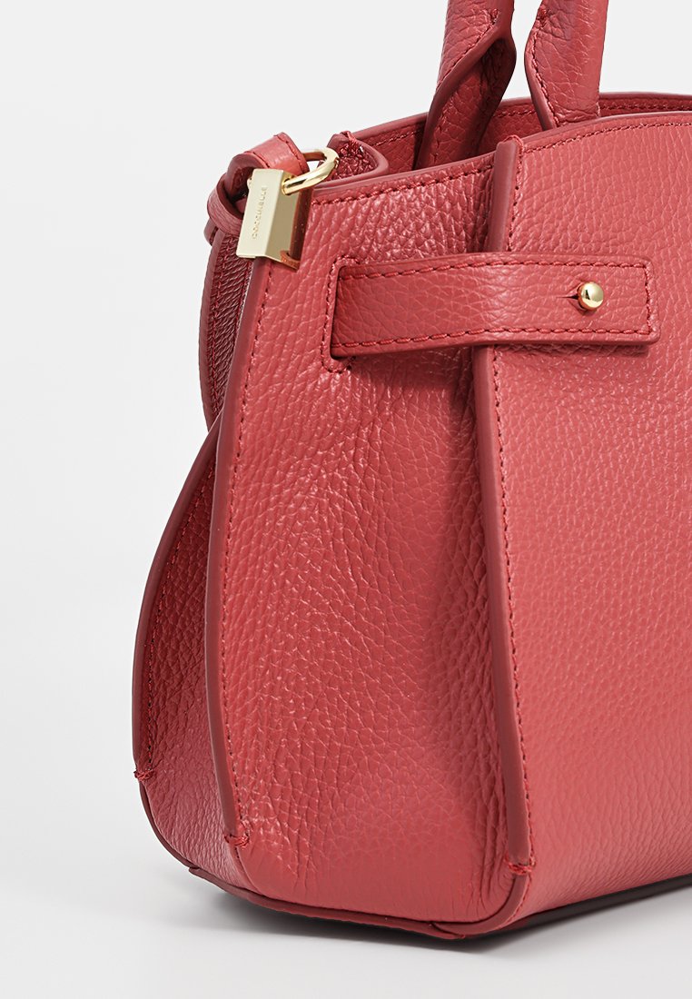 Borsa in pelle rossa con finitura testurizzata. Presenta una zip sicura, hardware dorato e una forma strutturata con manici corti.