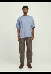 Ανοιχτό μπλε oversized t-shirt με κοντά μανίκια, σε συνδυασμό με καφέ παντελόνι σε φαρδύ στυλ και καφέ παπούτσια με κορδόνια. Απλή, χαλαρή εφαρμογή.