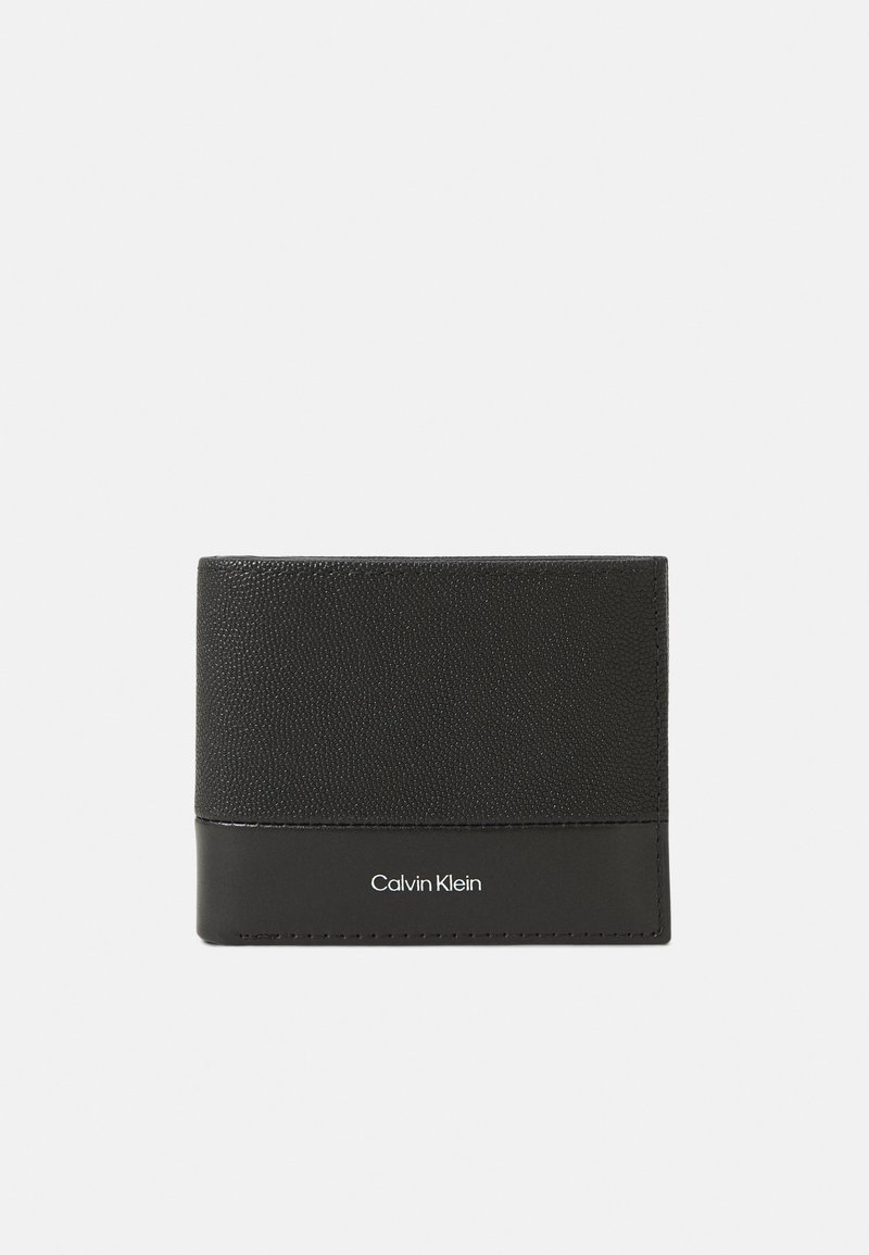 Billetera de cuero negro con parte superior texturizada, parte inferior lisa y logo "Calvin Klein" en relieve. Diseño compacto con forma rectangular.