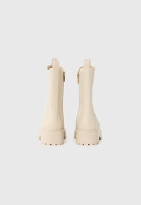 Beige ankelstøvler med en glat, blank finish, som har en sidelukning, minimal søm og en kraftig, teksturert såle.