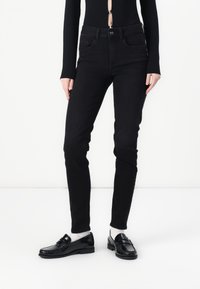 Sorte skinny jeans laget av denim, med en klassisk fem-lomme design, jevnt tekstur, og en enkel knapp- og glidelås-lukking.
