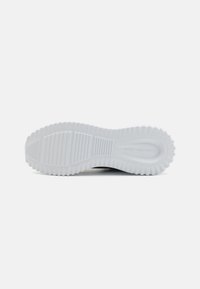 Semelle de sneaker en caoutchouc blanc avec un motif strié, comportant une section centrale lisse et un bord texturé pour une meilleure adhérence.