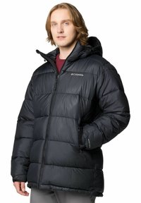 Giacca puffa nera isolata con zip frontale, cappuccio e polsini elasticizzati. Presenta un motivo cucito e un logo sul lato sinistro del petto.