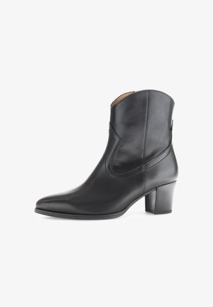 Schwarze Leder-Ankle-Boots mit spitzer Zehenpartie, geschwungenen Ausschnitten und einem mittelhohen Blockabsatz. Glatte Textur und minimalistische Designdetails.