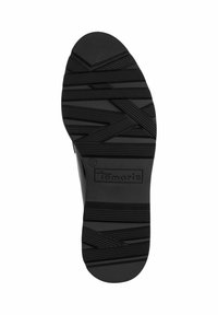 Black rubber shoe sole with textured grooves and cross-hatch pattern; features embossed brand name "Tamaris" and size "37."